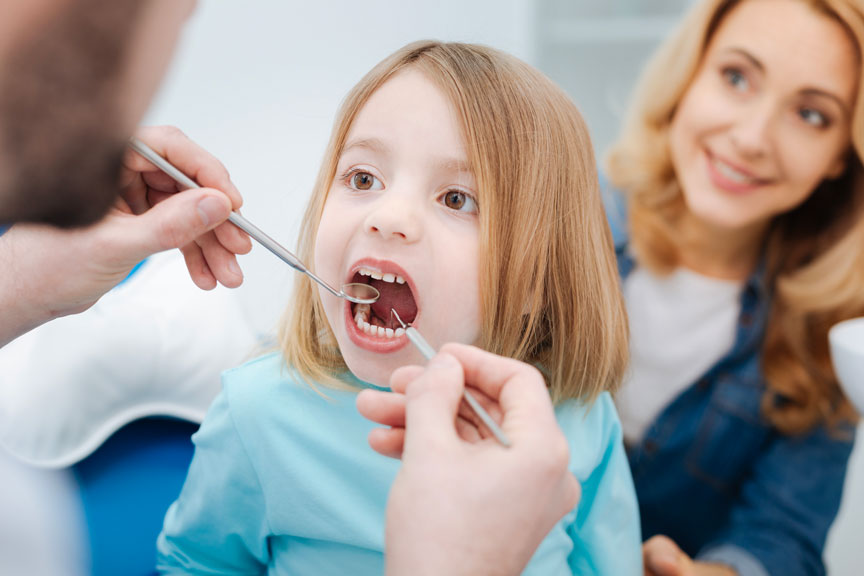 Dentist Checking Kid's Dental Health With Her Mom By Her Side